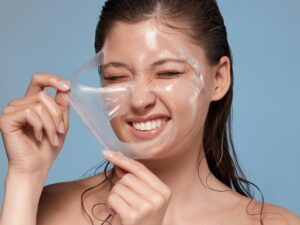 woman removing with hardness her facial mask and smiling